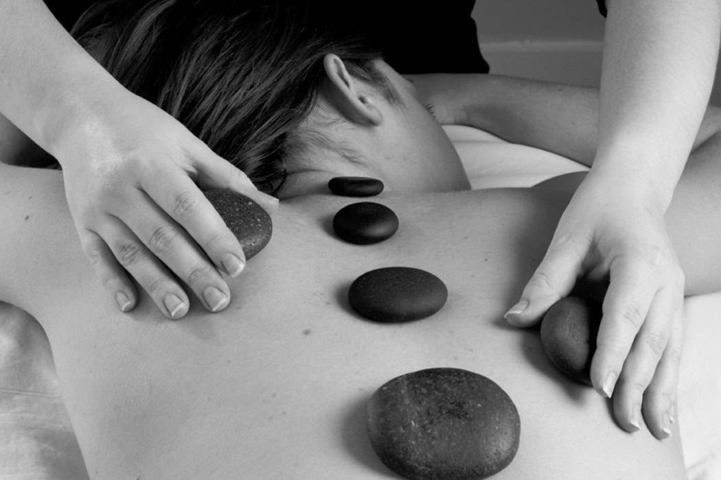 Sydney performs a hot stone massage on a client's back.