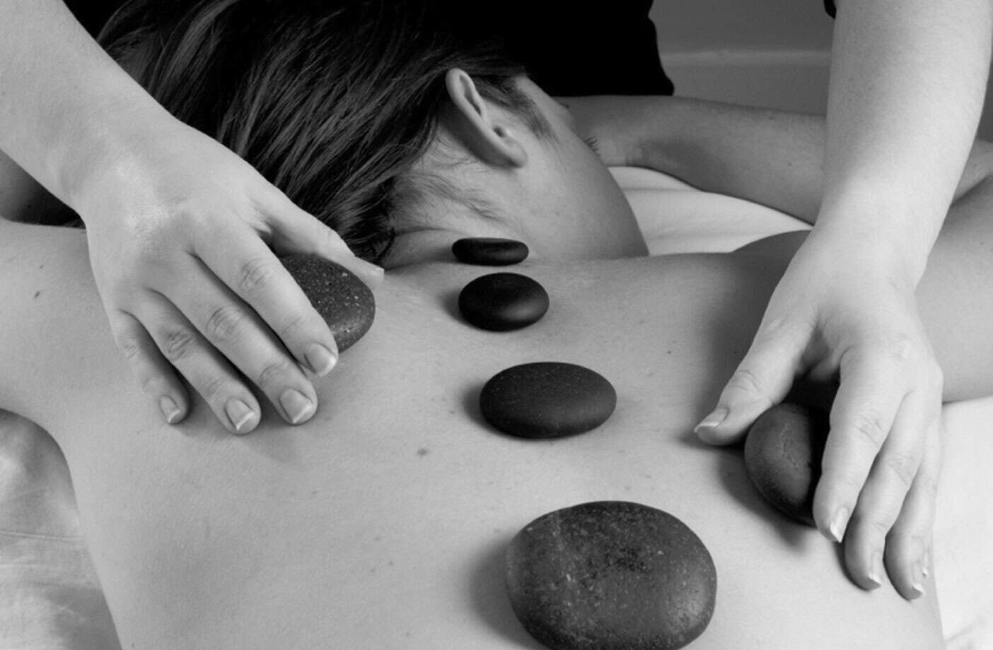 Sydney massages a client's back using hot stones.